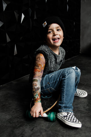 Kid playfully sticks tongue out showing his full temporary tattoo sleeve