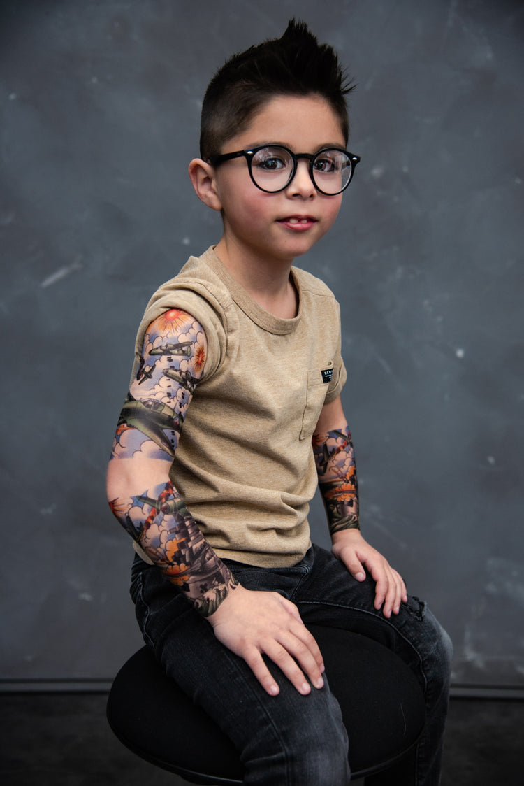 Boy with glasses shows off fake tattoos with planes bombing a navy ship