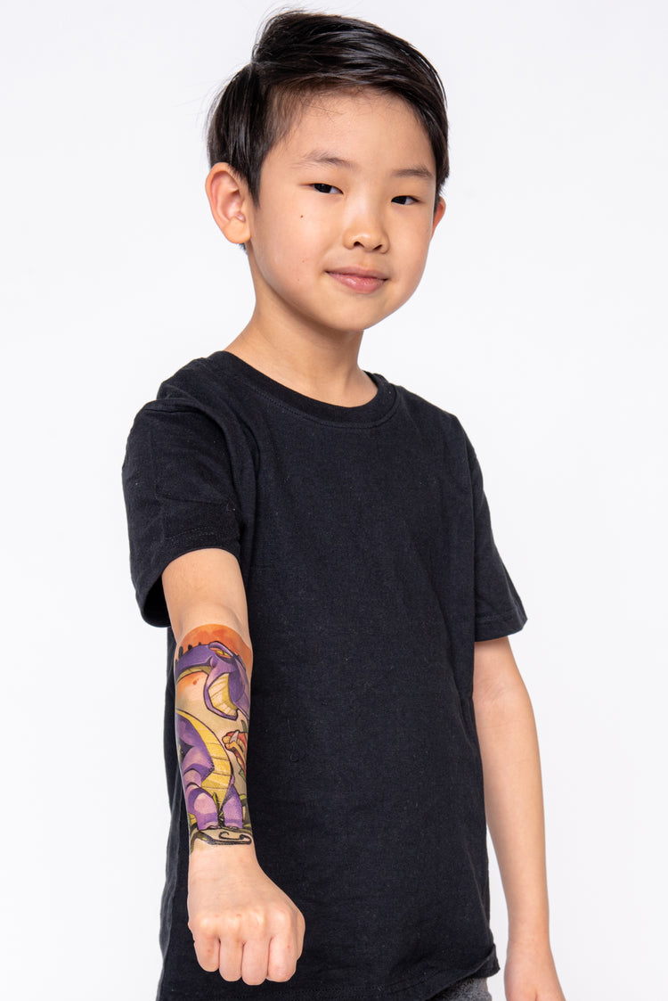 Young boy shows off his lower arm temporary tattoo sleeve with  a brontosaurus