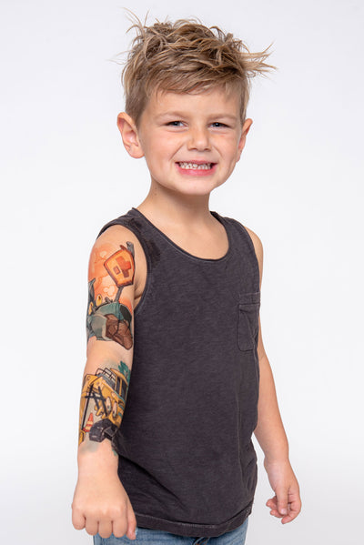 Young boy shows off temporary tattoo sleeve with construction equipment.