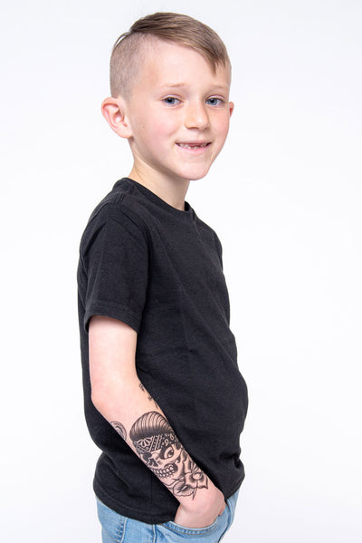 Young boy shows off forearm sleeve of a fake tattoo with a Chicano style.