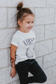 Young girl leans against the wall showing her fortune tattoo on her forearm.